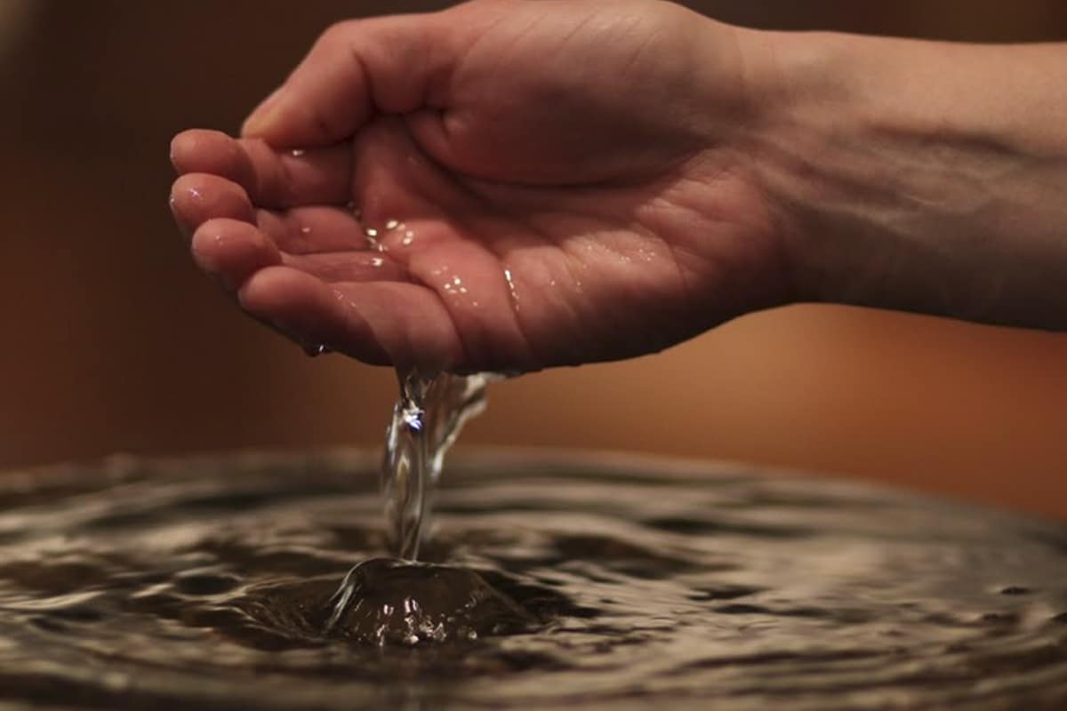 Imagen de una ano tocando agua bendita tras realizar una oración